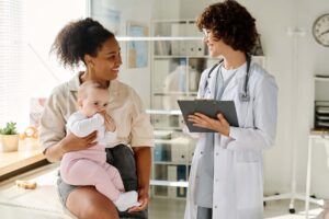 New mom holding her infant during office visit with her doctor.