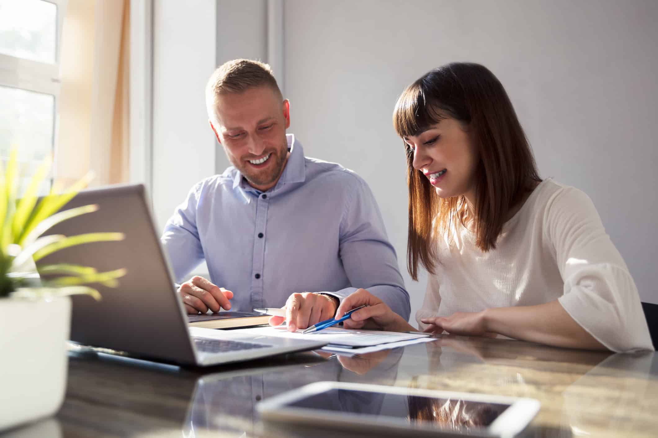 Couple working together on their laptop and analyzing paperwork.