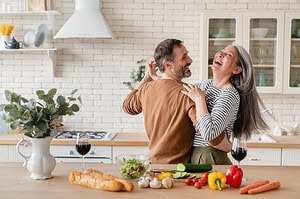 Middle aged couple dancing in the kitchen, laughing and enjoying time together. Active seniors.